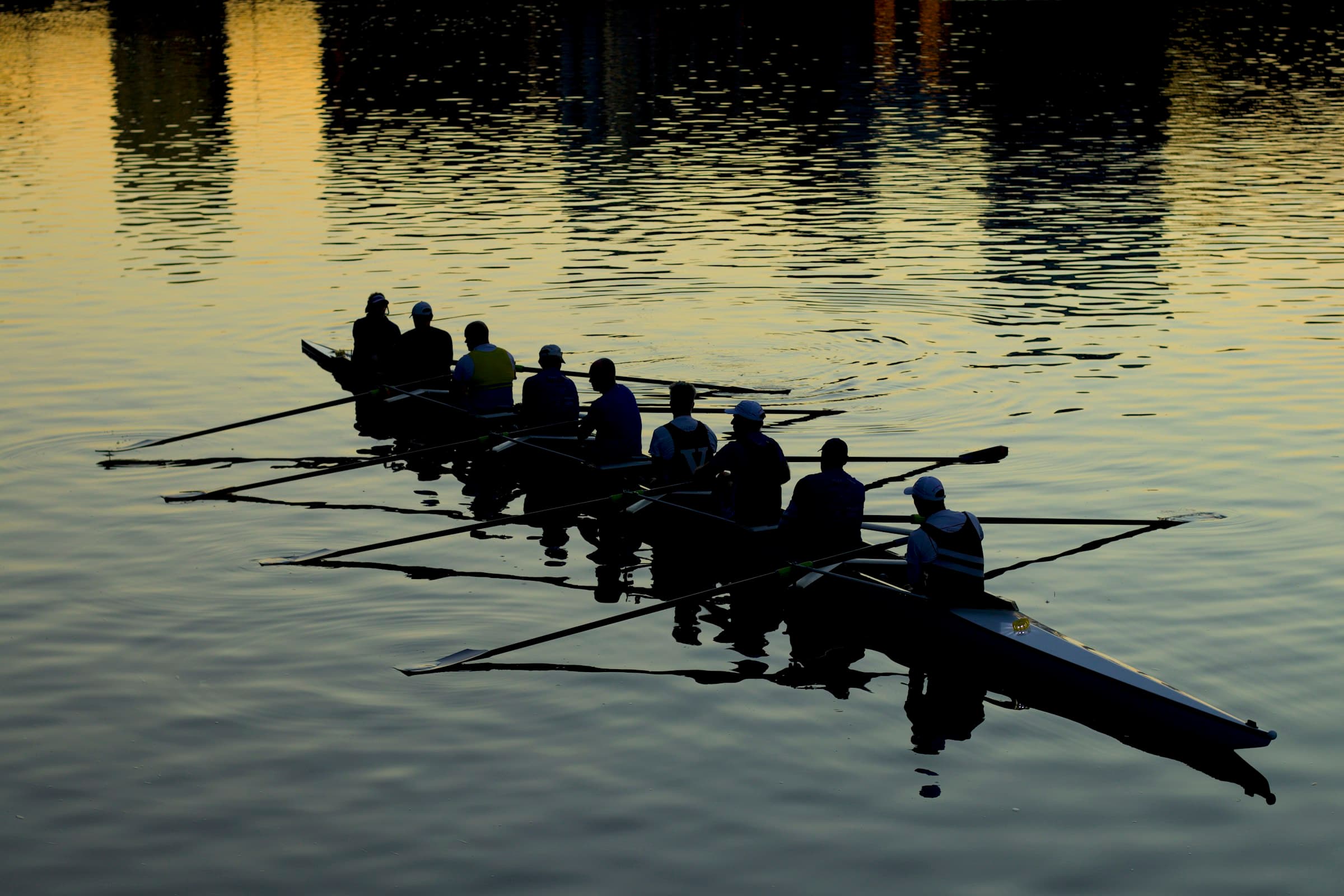 A rowing eight silhouetted against still water at dawn